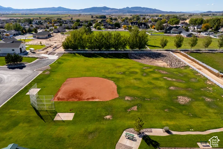 Expansive green space featuring a baseball diamond, perimeter fencing, and mature trees