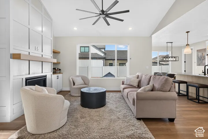 Integrated living area featuring wood-finish flooring, a contemporary ceiling fan, and a built-in fireplace with custom cabinetry