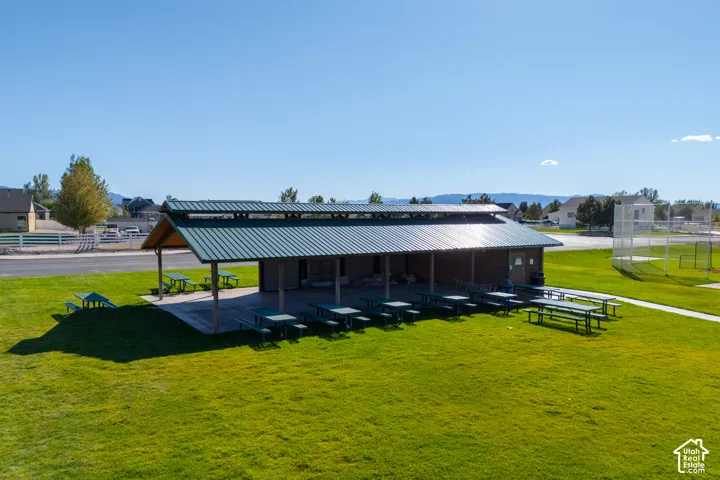 Expansive green space featuring a large pavilion with a metal roof, concrete patio, and built-in seating