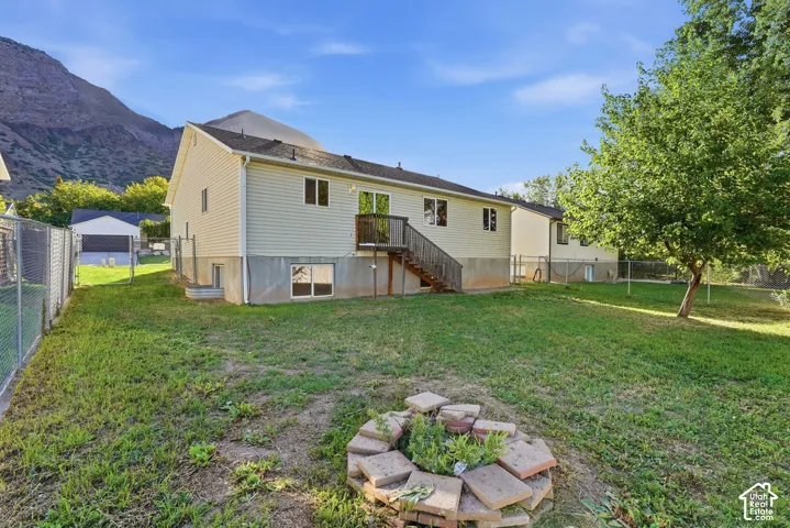 Expansive backyard with a green lawn, mature tree, and chain-link fencing