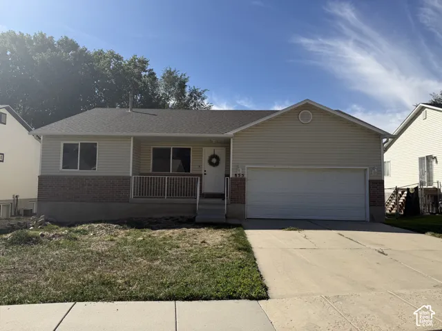 Front exterior featuring horizontal siding, brick accents, a covered porch with white railings, a concrete driveway, and an attached garage