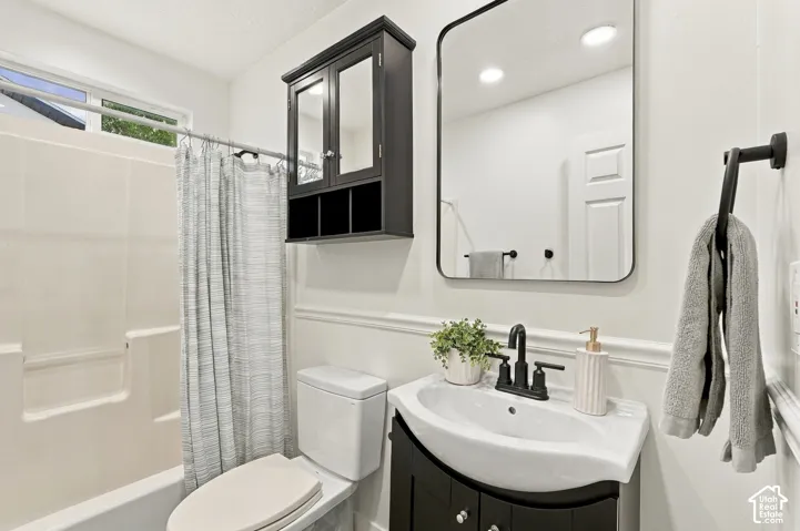 Bathroom featuring a white bathtub, toilet, and vanity with a black base