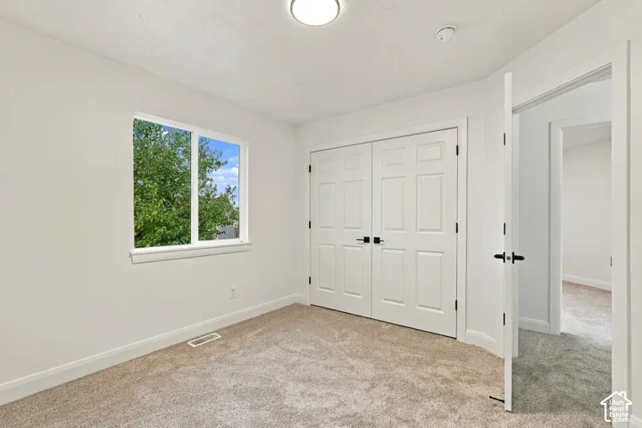 Neutral wall paint with textured carpeting, a white window frame, and white panel doors with matte black hardware