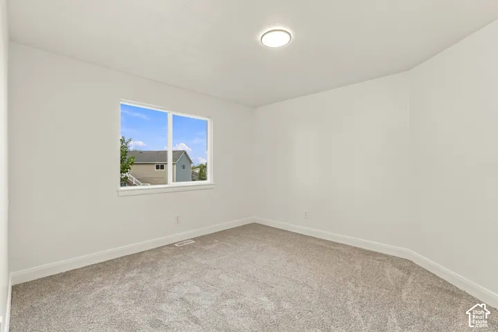 Neutral wall color, carpeted flooring, window with white trim, and a ceiling-mounted light fixture