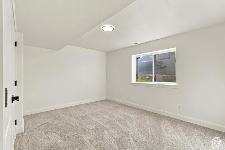 Recessed lighting, light-colored carpet, white walls, white trim, and a window