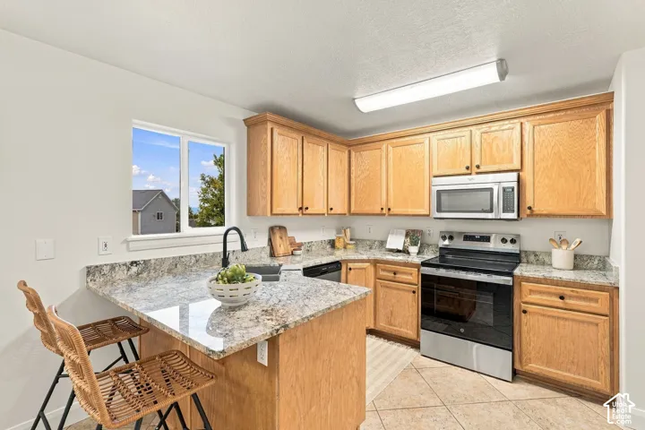 Kitchen featuring light wood cabinetry, granite countertops, a stainless steel range, and a stainless steel microwave