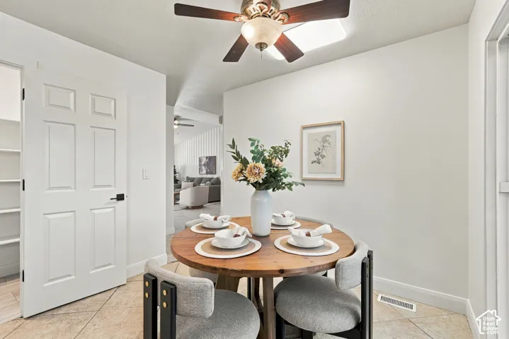 Tile flooring, white paneled door, built-in shelving, ceiling fan light fixture, and white wall finishes