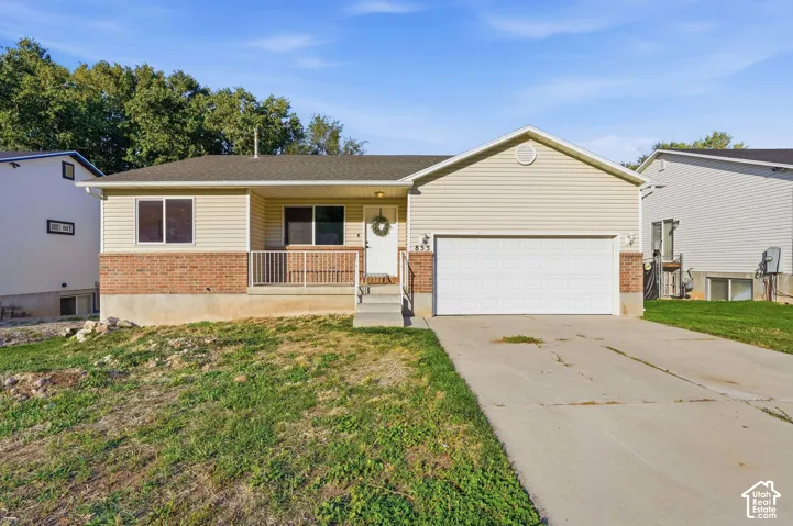 Brick and siding exterior featuring a covered front porch with railing, a two-car garage, and a concrete driveway