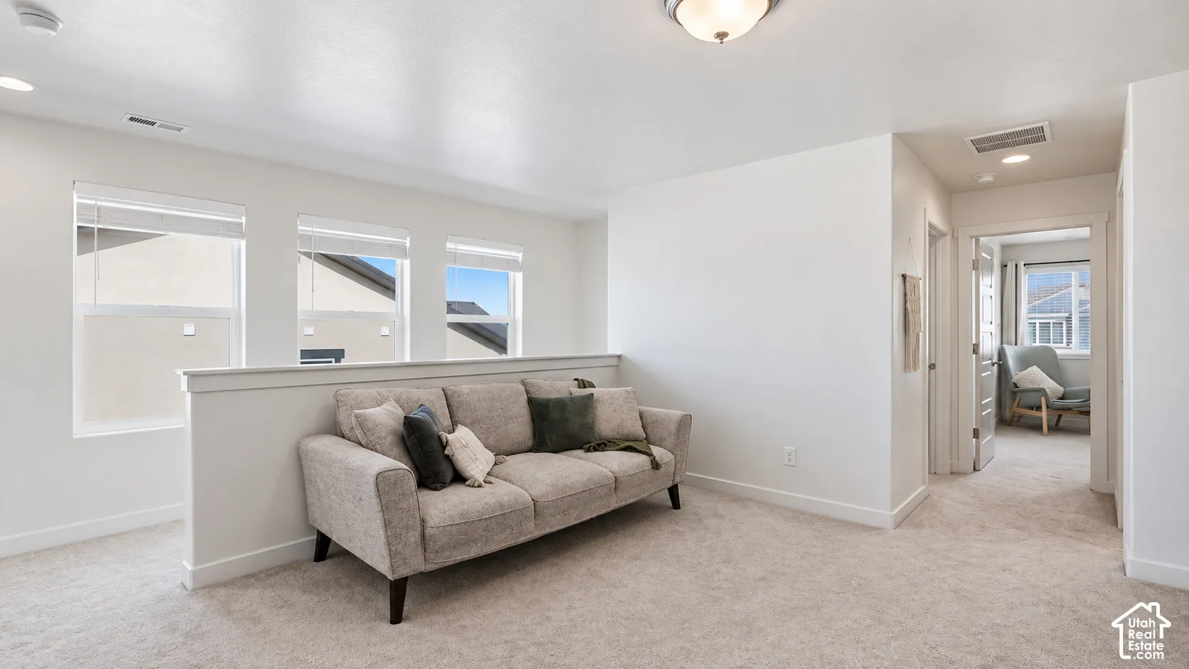 Interior space featuring neutral wall tones, wall-to-wall carpeting, three multi-pane windows with integrated blinds, and a half-wall partition