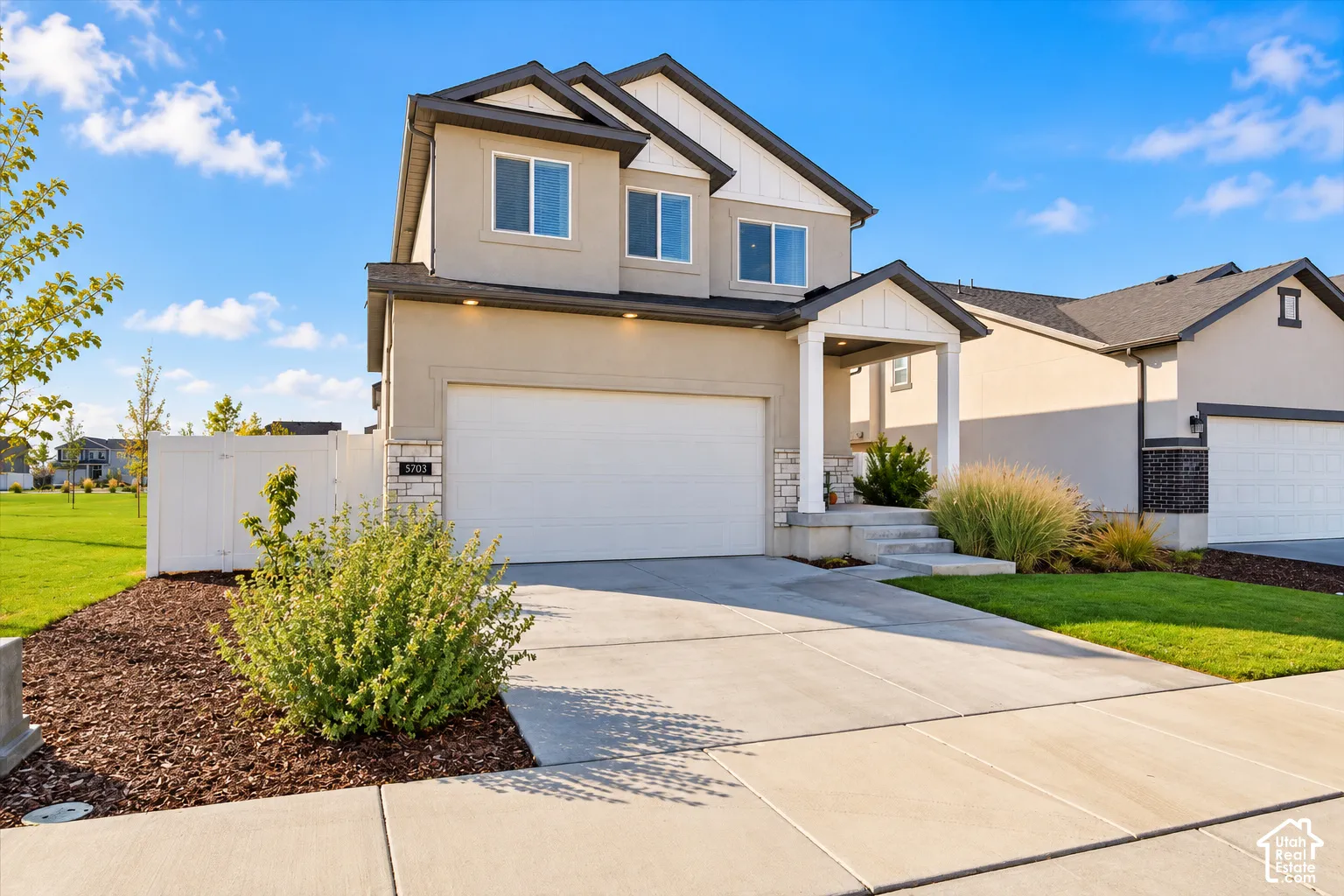 Two-story residence featuring a stucco and stone exterior, gabled roofline, covered front porch, and a two-car garage