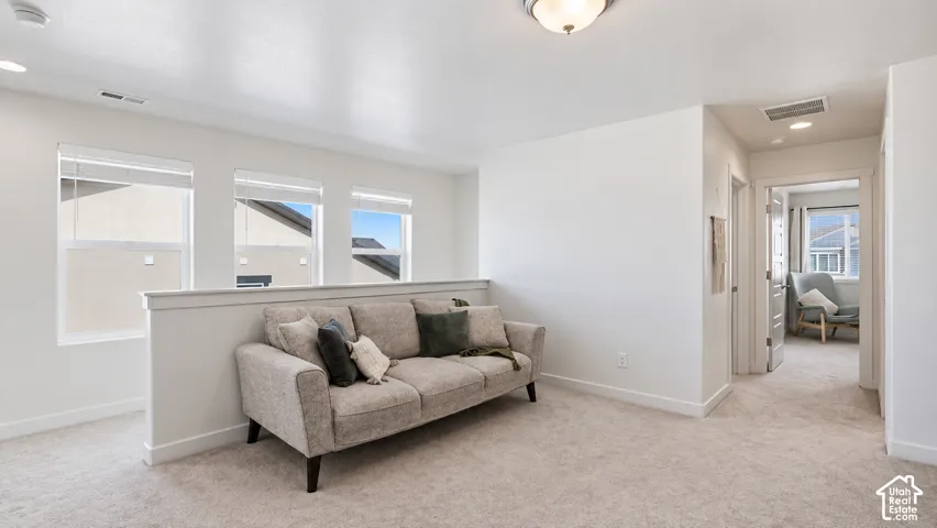 Interior space featuring neutral wall tones, wall-to-wall carpeting, three multi-pane windows with integrated blinds, and a half-wall partition