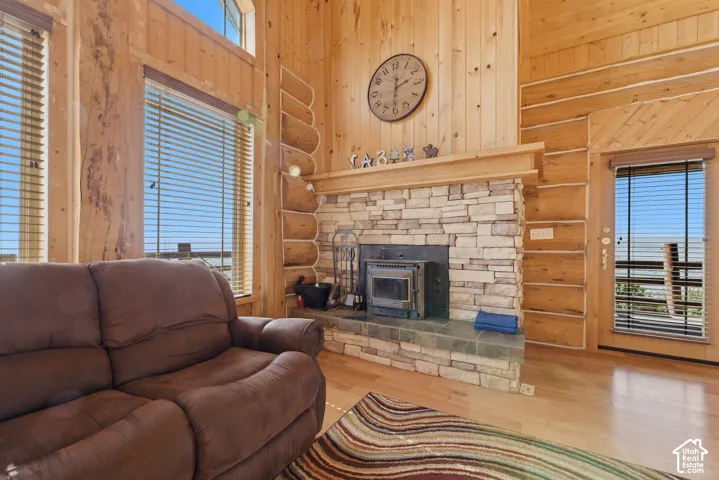 Vaulted natural wood-finish ceilings, wood-finish flooring, stone-clad fireplace with wood-burning insert, and large windows with blinds