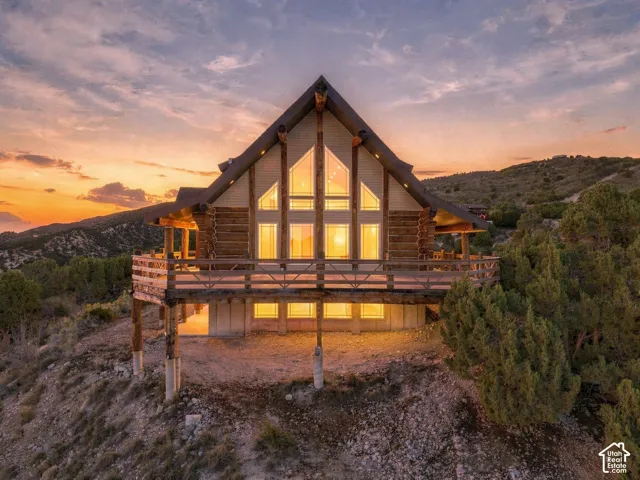 Log cabin style exterior with a steep gabled roof, prominent A-frame window design, and an expansive wrap-around deck