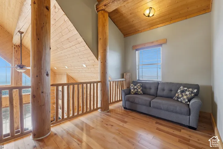 Vaulted wood-finish ceilings, wood-finish flooring, log beam accents, and natural wood railing