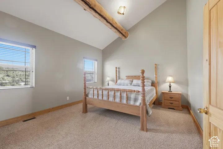 Vaulted ceiling with an exposed wood beam, two windows with blinds, and light-toned wall paint