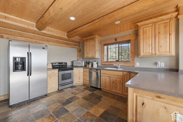 Kitchen featuring wood cabinetry, stainless steel appliances, durable countertops, tiled flooring, and wood-paneled ceilings with exposed log beams