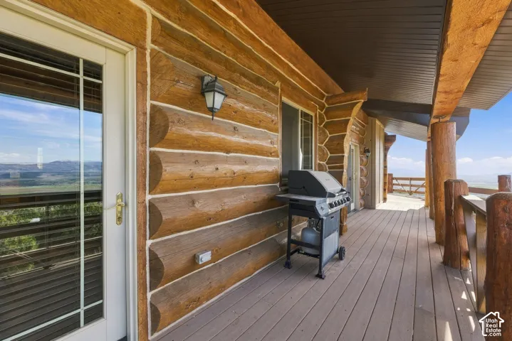 Log cabin exterior with a covered porch featuring wood-finish decking and a wooden railing