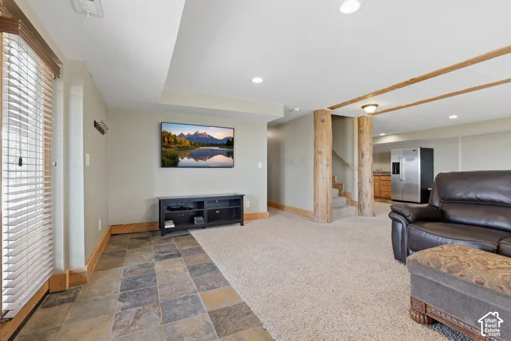 Recreational area featuring mixed flooring with stone tile and carpeting, recessed lighting, and exposed wood beam accents