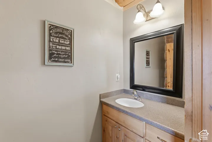 Single vanity with wood-finish cabinetry, integrated sink, and countertop