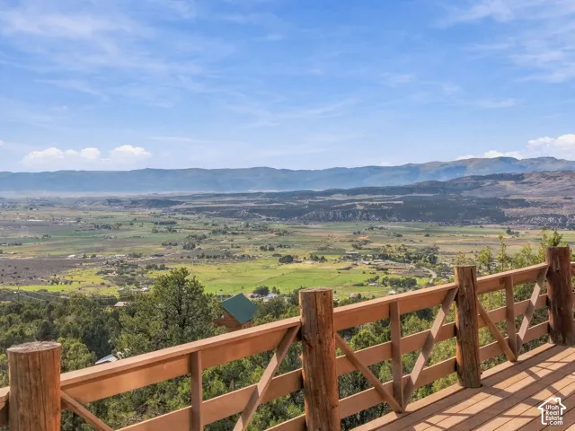 Expansive wooden deck with a rustic-style railing, offering a panoramic mountain and valley backdrop