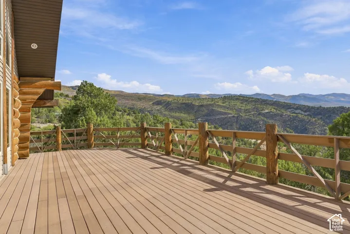 Expansive deck featuring wood-finish flooring, a wood rail, and log cabin-style exterior siding