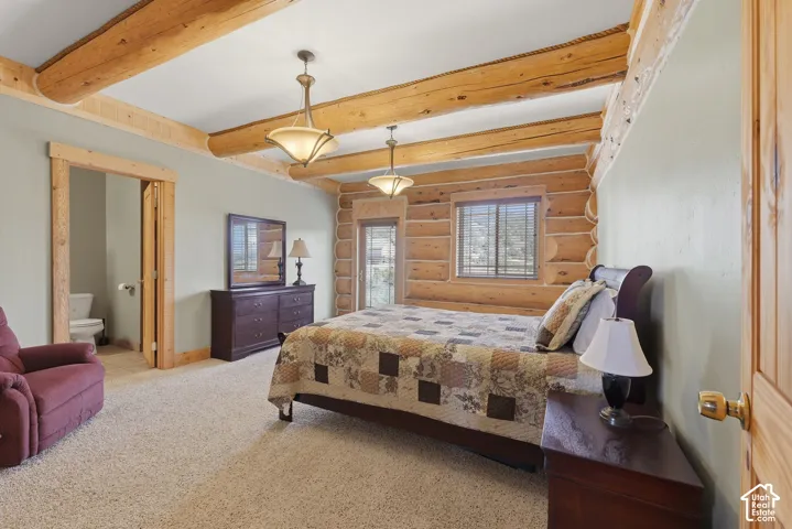 Exposed log beams, light-colored carpeting, log wall finishes, and a wood-framed window