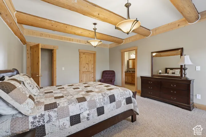 Exposed wood beams, neutral wall tones, wood-finish doors, two semi-flush mount light fixtures, and carpet flooring