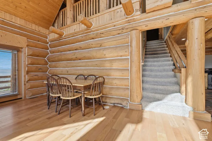 Log construction interior with wood-finish flooring, a window with horizontal blinds, and a carpeted staircase