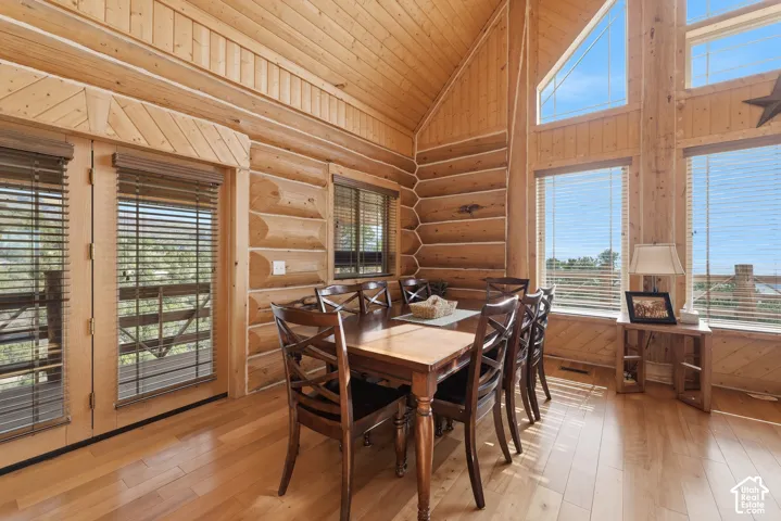 Vaulted wood-paneled ceiling, exposed log wall construction, wood-finish flooring, ample natural light, and expansive windows