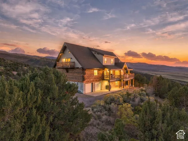 Log cabin exterior with multiple balconies, a lower-level garage, and an expansive mountain backdrop