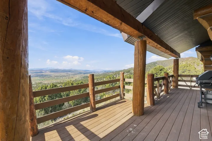 Expansive outdoor deck featuring wood-finish flooring, substantial wood support beams, and a wood railing overlooking a distant landscape