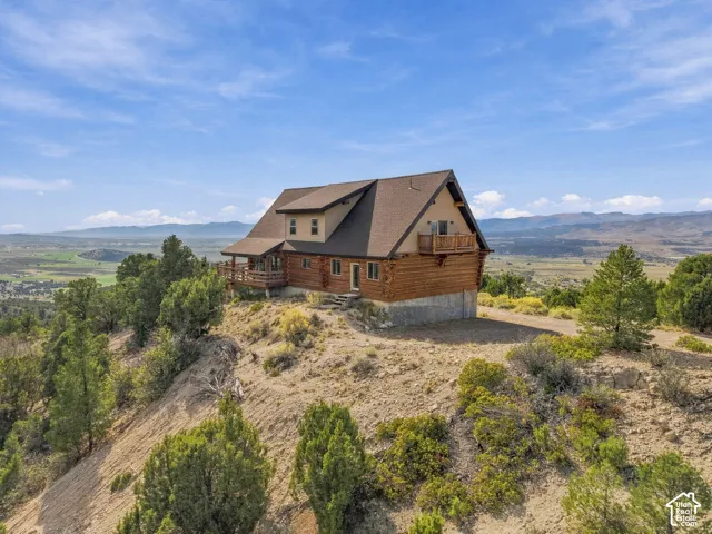Log home exterior with a pitched roof, multiple balconies, and an elevated foundation