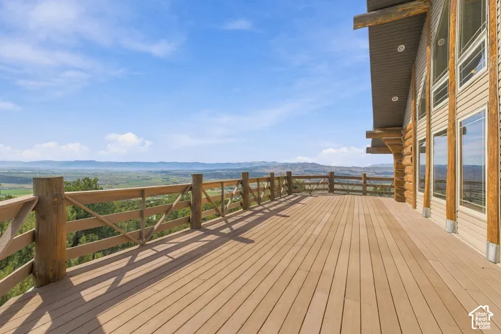 Expansive outdoor deck with wood-finish flooring, framed by a natural wood railing