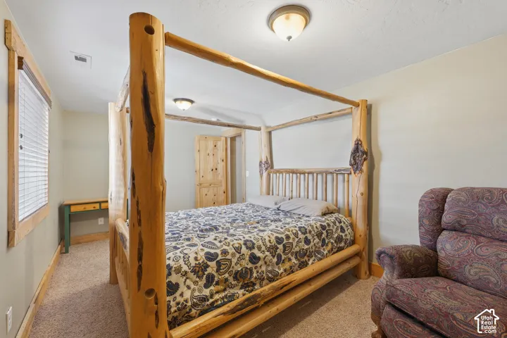 Carpeted room with a wooden framed window, a natural wood-finish door, and flush-mount ceiling lighting