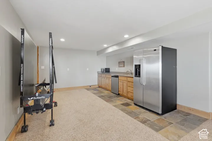 Built-in wet bar with wood-finish cabinetry, stainless steel appliances, and a rectangular sink