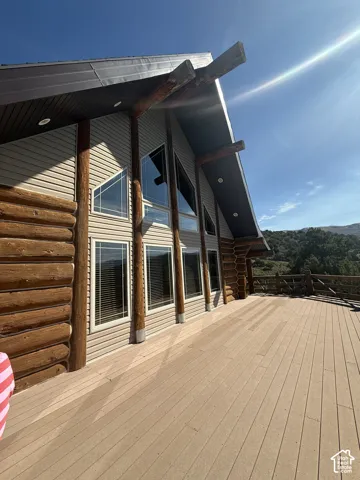 Expansive outdoor deck with composite decking, log beam accents, large windows, and a metal roof