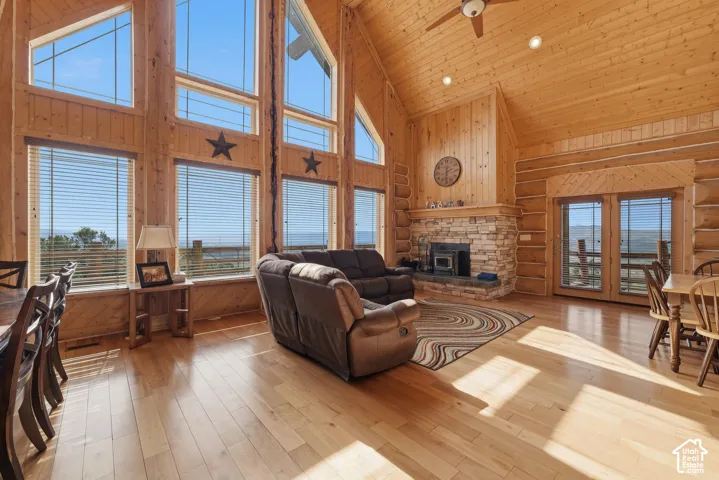 Hardwood flooring, vaulted wood-paneled ceiling, stone fireplace, and French doors