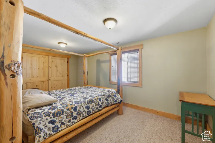 Wall-to-wall carpeting, wood-trimmed window with blinds, and built-in wood closet doors