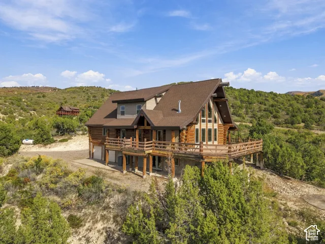 Log cabin exterior with a multi-level deck, pitched roofline, large window array, and natural wood railings