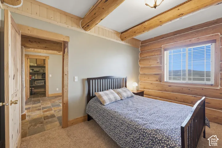 Log wall construction, exposed log ceiling beams, wood-finish interior door, wood-finish trim, and multi-tone tile flooring