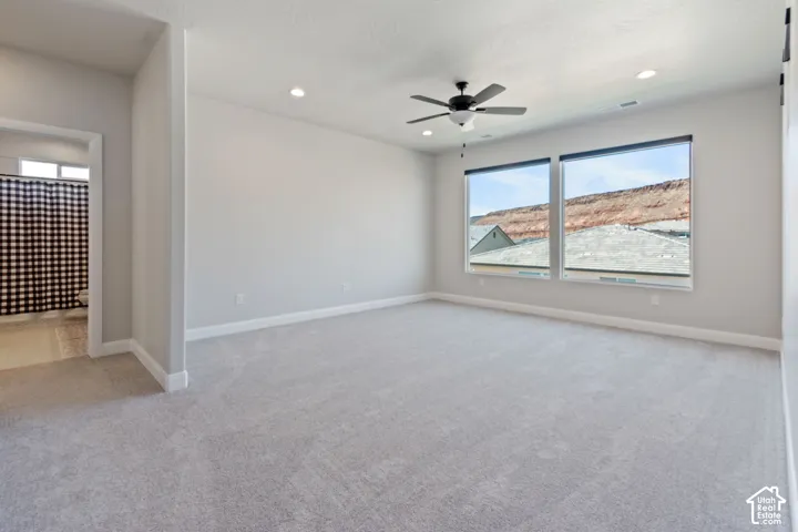 Spacious room with light gray carpeting, recessed lighting, and a ceiling fan