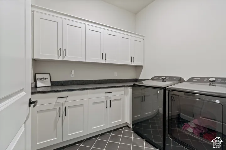 Full-height white cabinetry with black hardware, dark countertop, and dark tiled flooring