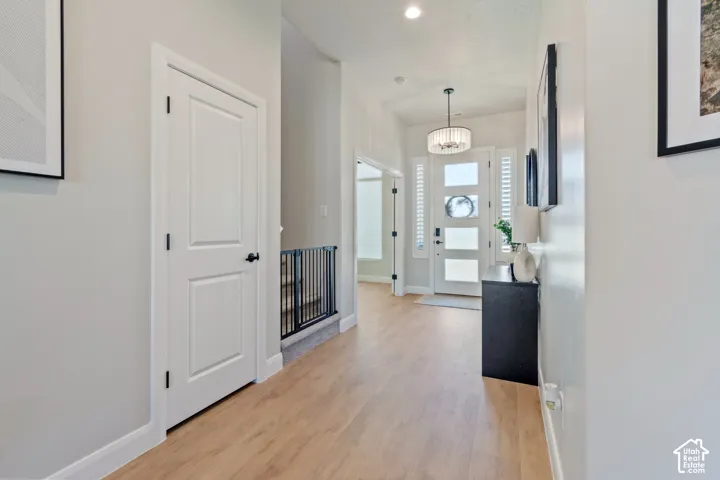 Entryway featuring wood-finish flooring, white panel doors, and a decorative chandelier