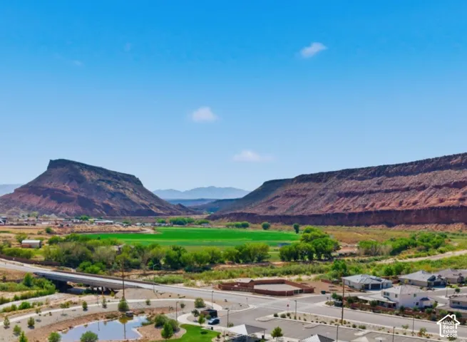 Expansive mountain backdrop with a flat-top mesa, a lush green valley, and developed residential areas