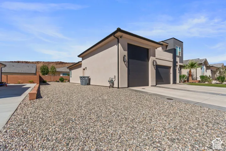 Contemporary exterior with a stucco finish, two garage doors, and a gravel and concrete driveway