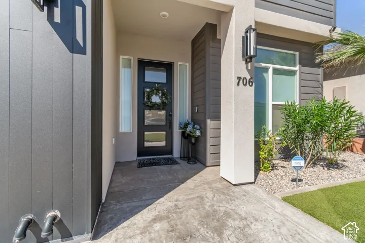 Modern exterior featuring a dark entry door with frosted glass panels, an exterior wall light fixture, and a stucco finish