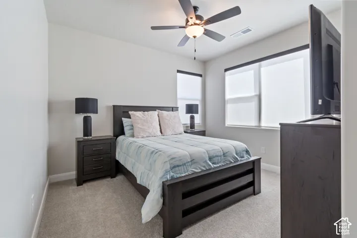 Carpeted flooring, neutral wall tones, recessed lighting, ceiling fan with integrated lighting, and multiple windows with roller shades