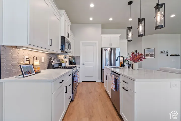 Kitchen featuring white cabinetry with black hardware, wood-finish flooring, recessed lighting, pendant lighting, and a tile backsplash