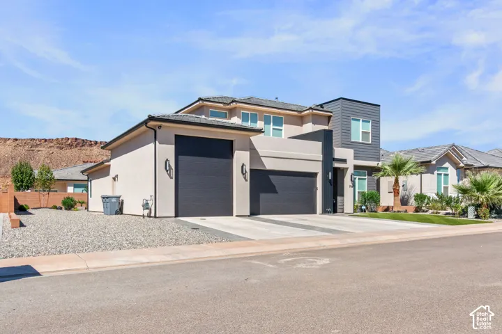 Contemporary architectural design featuring a multi-tone exterior, attached two-car garage, and a paver driveway