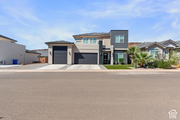 Contemporary two-story exterior with a flat roofline, two integrated garages, landscaped front yard, and a varied facade of stucco and dark paneling